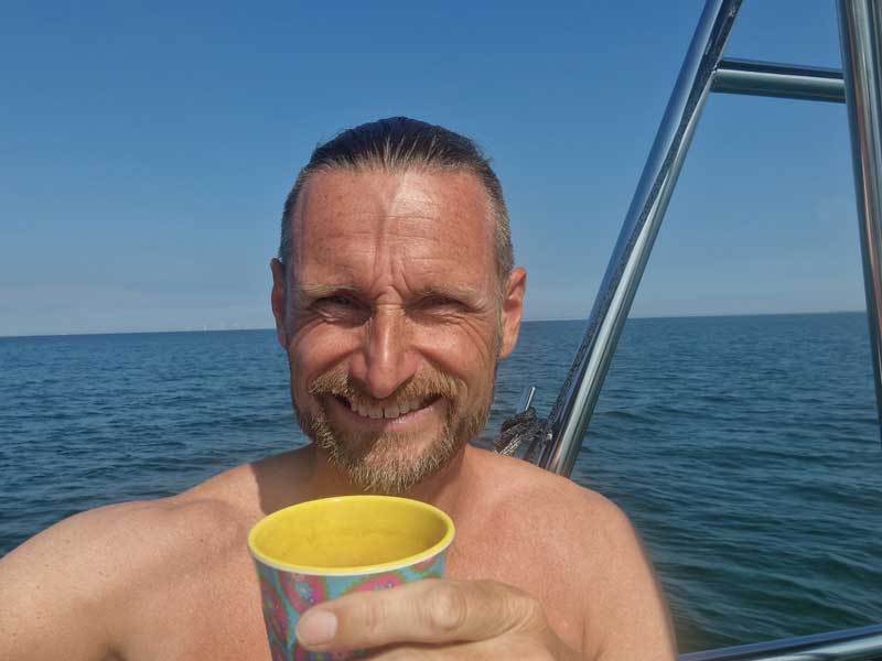 Thomas holder en kop om bord med havet i baggrunden